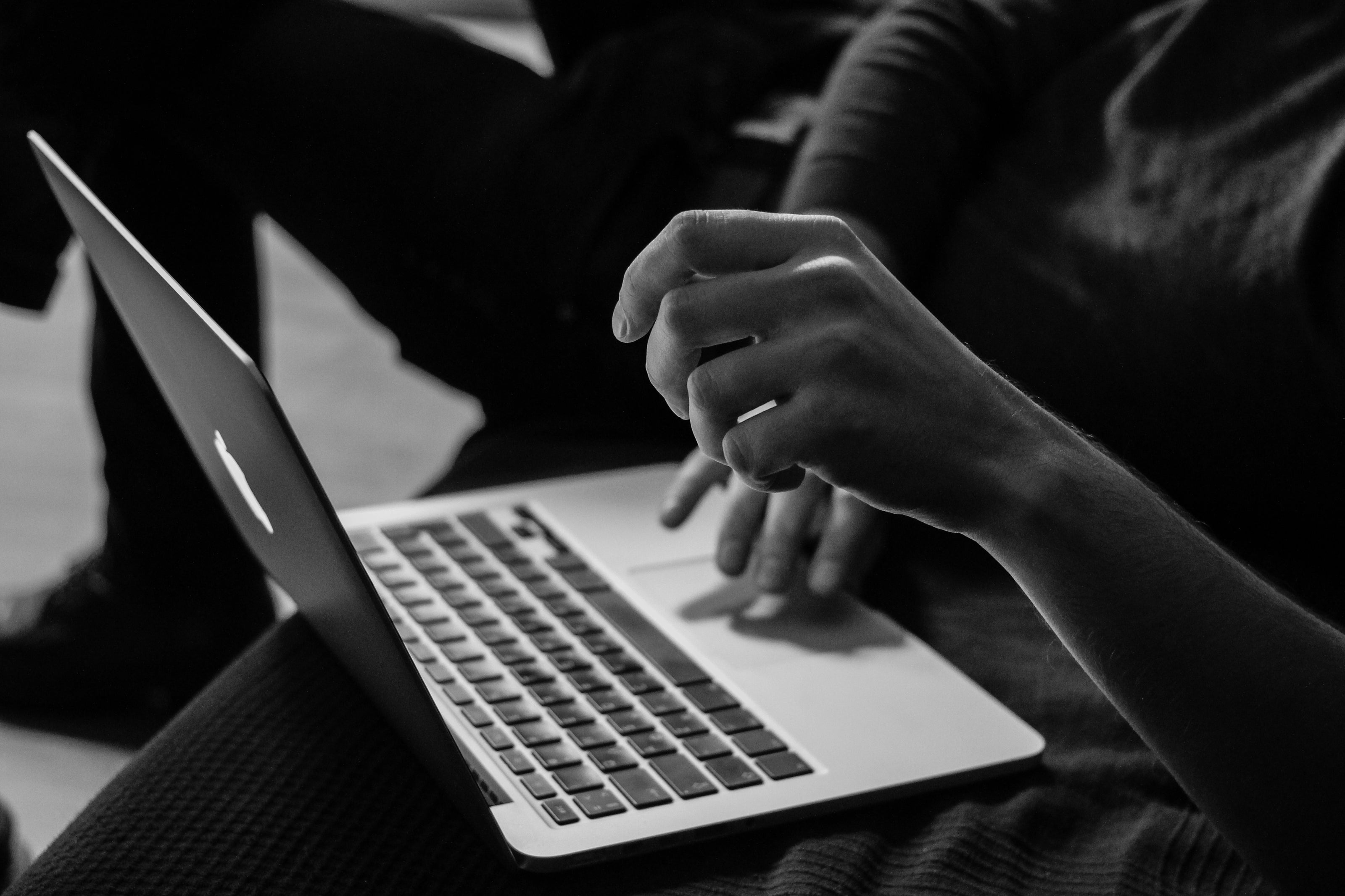 Person using a laptop with hands on the keyboard, black and white photo