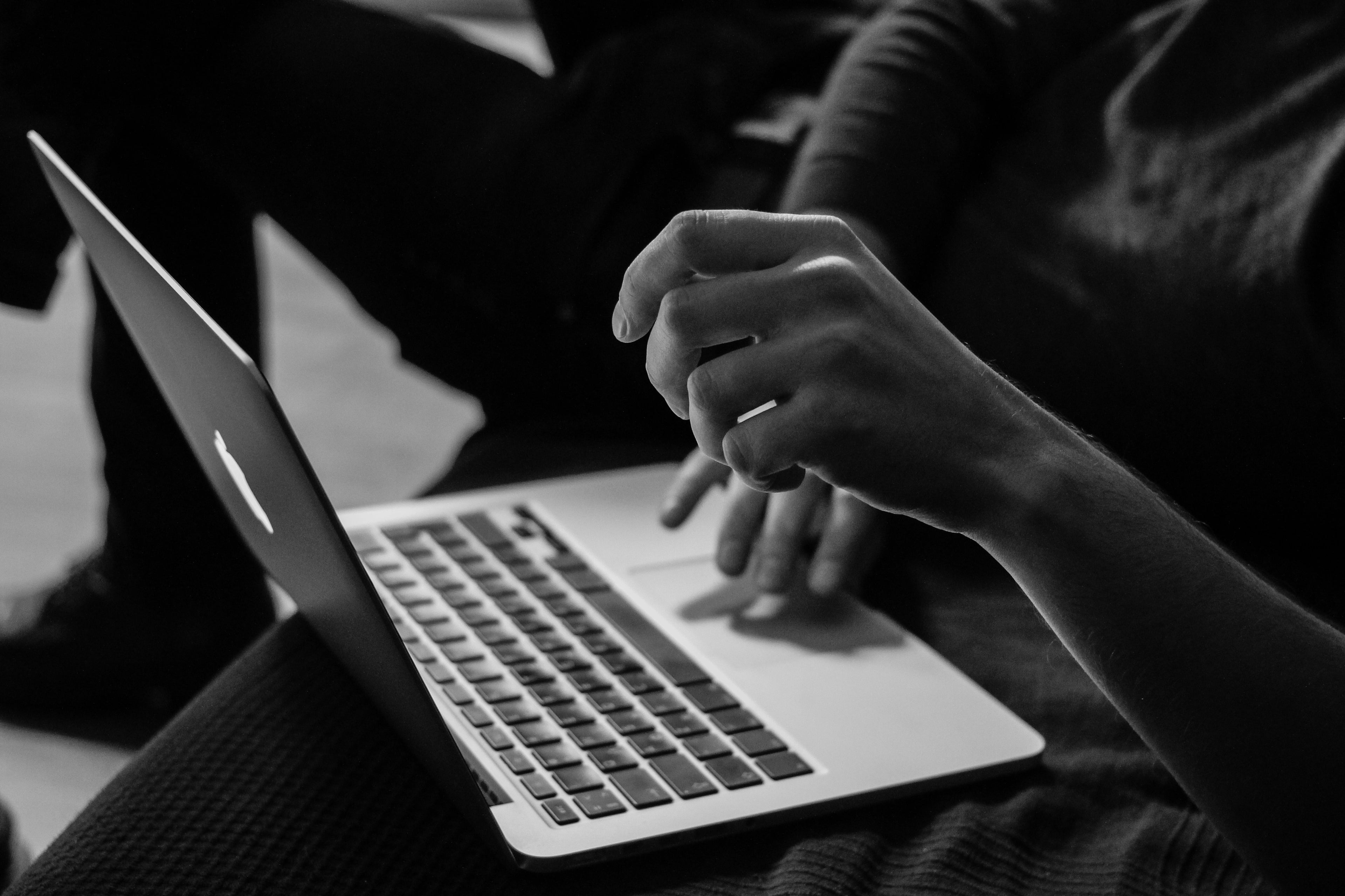 Person using a laptop with hands on the keyboard, black and white photo